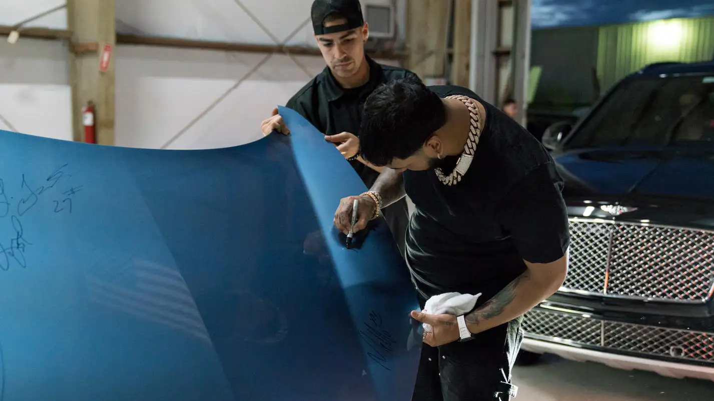 anuel aa signing the ferrari hood from mph club