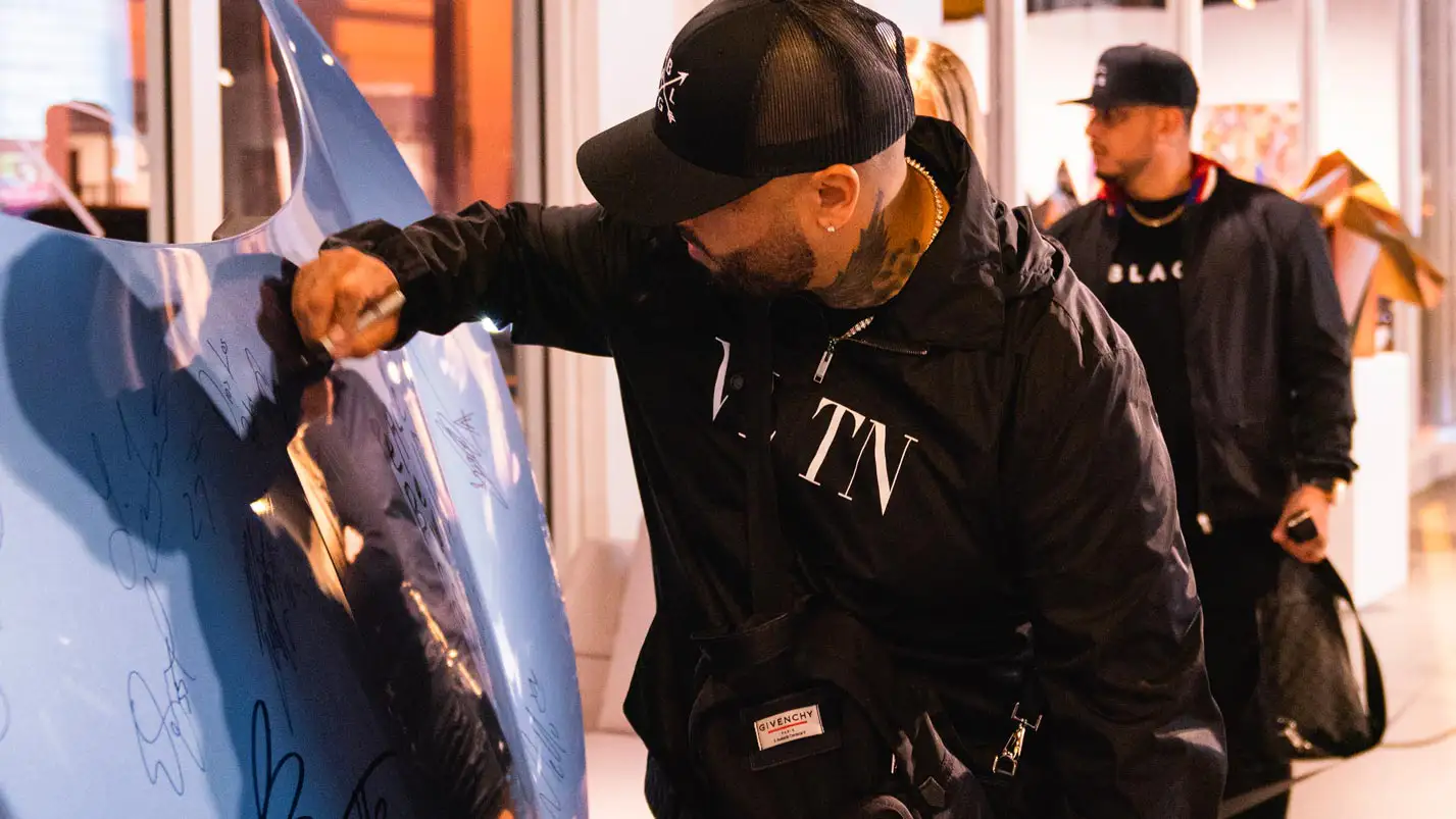 nicky jam signing the ferrari hood from mph club exotic car rental