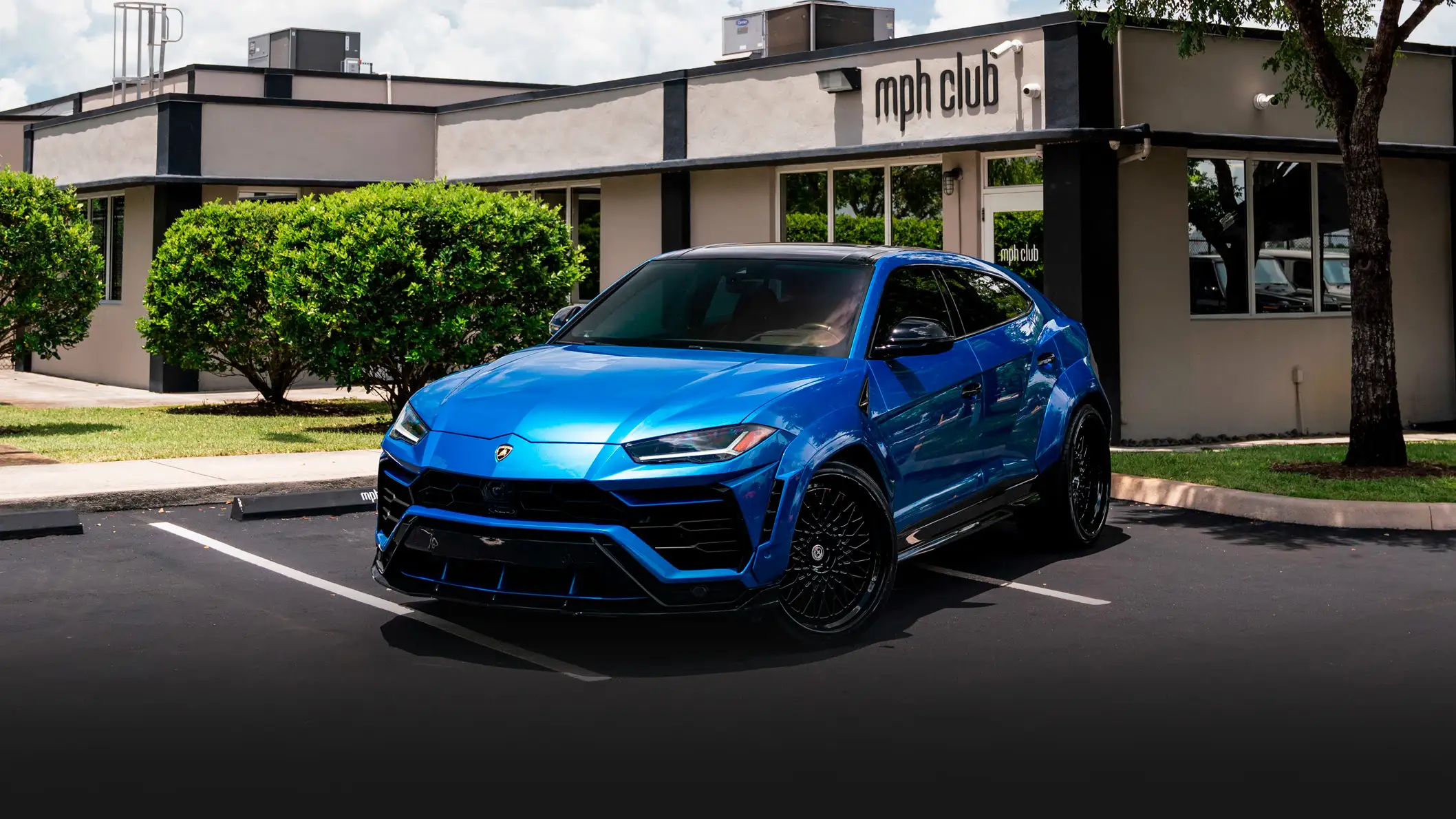 Lite blue Lamborghini Urus rental profile view mph club